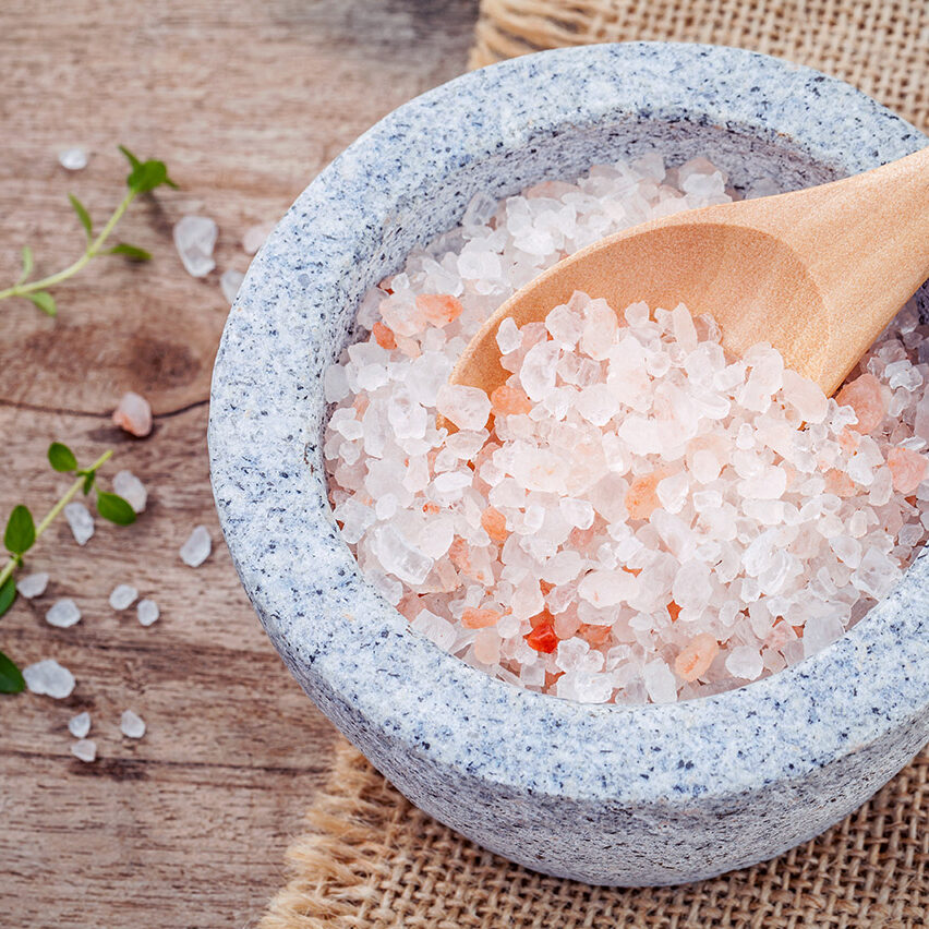 Himalayan pink salt in mortar with thyme on hemp sack background. Himalayan salt commonly used in cooking and for bath products such as bath salts.